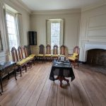 Antique room with wooden floors, vintage chairs, and a fireplace mantel.