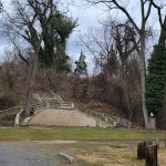 Stone steps ascend a wooded hillside under an overcast sky.