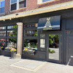 Exterior storefront of Agricola, a restaurant with large windows and dark facade.