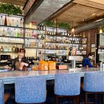 Bar interior with shelves of liquor, bartender working behind the counter.