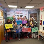 Group of people celebrating after an escape room challenge, posing with a banner.