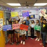 Group of people celebrating after an escape room experience with signs.