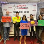 Group of five people posing in front of an "Amazing Escape Room" banner.
