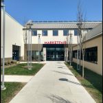 Modern commercial building entrance with "MARKETFAIR" sign and sunny walkway.
