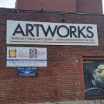 Brick building featuring "ARTWORKS" sign, promoting visual art center events.