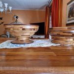 Two wooden bowls on a polished brown table, with an interior room visible in the background.