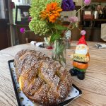 Sweet braided bread with cinnamon sugar next to a festive Santa figurine and flowers.