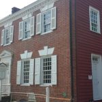 Historic brick and red clapboard buildings on a sunny street.