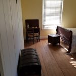 Interior room with wooden floors, a window with blinds, and vintage furniture.
