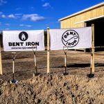 Bent Iron Brewing Company banner displayed in front of a wooden barn under a blue sky.