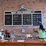 Brewery bar with a large menu board displaying beer options and prices.