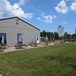 Modern barn venue with outdoor seating on a sunny, grassy field.