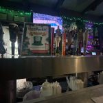Bar counter with beer taps, TV showing a game, and promotional materials.