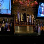 Bar area with TVs showing sports, featuring beer taps and liquor bottles.
