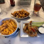 Plate of pasta, fried chicken, and roasted cubes on a marble tabletop.