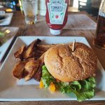 Cheeseburger and fries on a white plate with Heinz ketchup in the background.