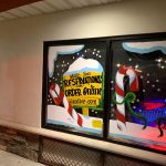 Two storefront windows display festive, holiday-themed advertisements for a blended drink shop.