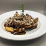 Savory pulled pork and roasted potatoes served on a white plate with gravy.