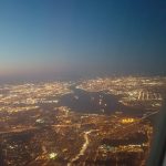 Nighttime aerial view of a sprawling city illuminated with lights under a dark blue sky.
