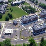 Aerial view of a modern, multi-building residential complex with green space and parking lots.