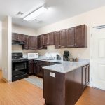 Modern kitchen with dark wood cabinets, granite countertops, and stainless steel appliances.