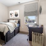 Modern bedroom with dark wood bed, abstract art, and a desk area by a window.