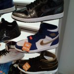 Assortment of Nike sneakers displayed on white shelves, featuring various colors and finishes.
