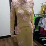 Mannequin wearing a beige outfit adorned with pink floral appliqués.