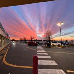 Vibrant sunset over a parking lot with dramatic pink and orange clouds.