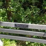 Trailblazer plaque mounted on a wooden fence surrounded by lush green foliage.
