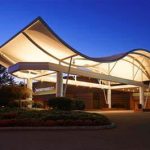 Modern, illuminated hotel entrance under a deep blue twilight sky.