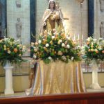 Statue of the Virgin Mary and child on an altar decorated with flowers inside a church.