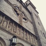 Stone facade of a historic church with carved figures and religious inscriptions.