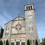 Stone church with clock tower under a blue sky.