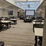 Modern, bright conference room with rows of tables and chairs set up for a meeting.