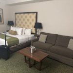 Modern hotel room with a bed, sofa, and side table.