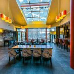 Bright, modern restaurant interior with high skylight and dark tile floor.