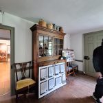 Antique wooden cabinet with glass doors and a display of framed art on the floor.
