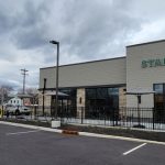 Starbucks storefront with modern facade under a cloudy sky, featuring outdoor seating.