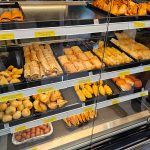 Display case filled with various fried Indian snacks like samosas, kachoris, and pakoras.