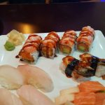 Assortment of sushi rolls and sashimi on a white plate.