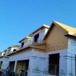 Framing of a new house under construction against a clear blue sky.