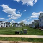 New suburban community with white houses, green lawns, and blue sky.