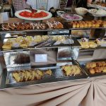 Buffet table laden with pastries, breads, and sweet treats for a gathering.