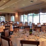 Elegant ballroom set for a formal event with round tables and white linens.