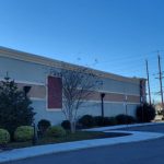 Modern commercial building with stone and stucco facade under a clear blue sky.