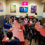 Children participate in a colorful classroom activity with artwork and bright decorations.