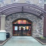 Stone facade entrance with arched awning and glass doors of a modern commercial building.