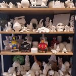 Shelf display of various white and colored miniature figurines, including superheroes.