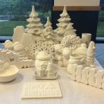 White ceramic Christmas village decorations and "Merry Christmas" letters on a table.